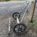 photo of a rolling flame weeder propped up against a post