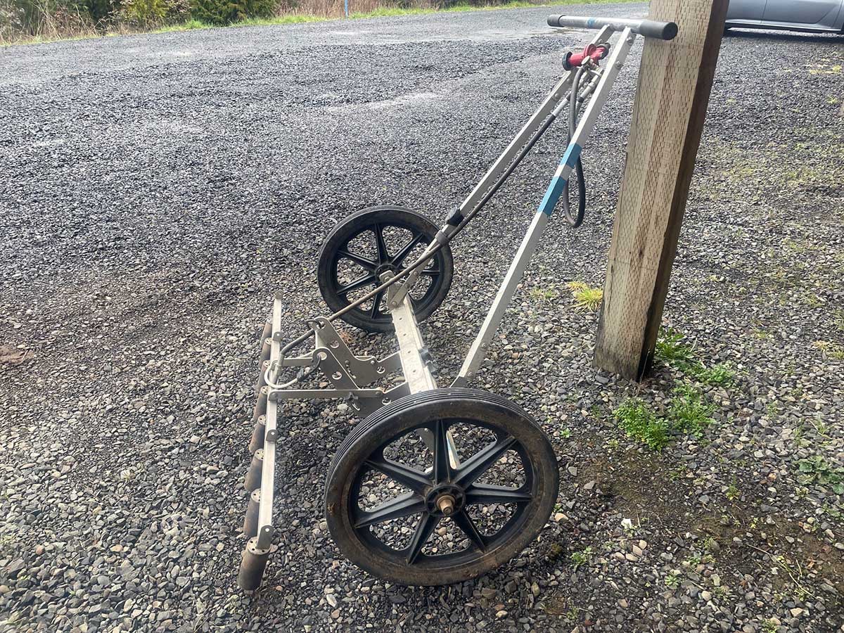 photo of a rolling flame weeder propped up against a post
