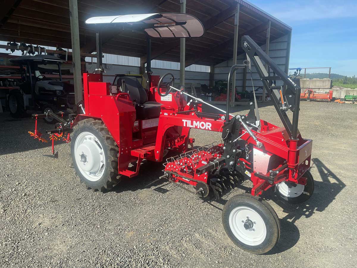 photo of a Tilmor cultivator tractor, with red paint and implements beneath the carriage between the wheels