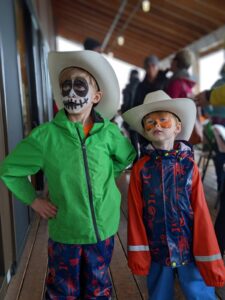 Two young boys wearing cowboy hats with faces painted.